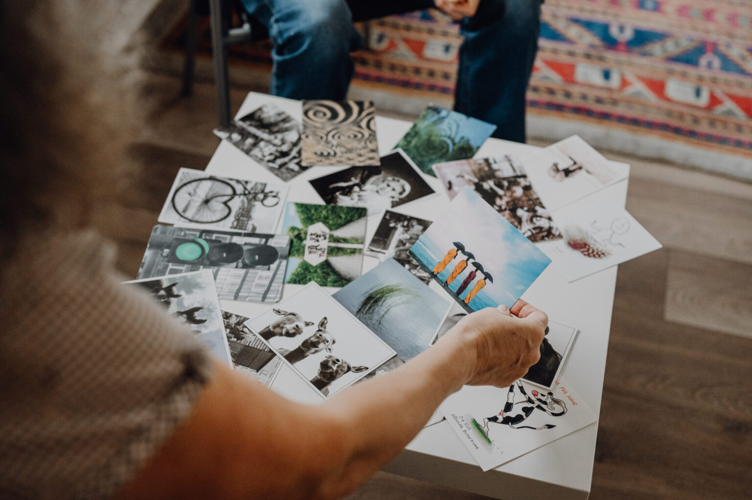 Hände legen bunte Bildkarten auf Tisch zur Visualisierung in Workshop-Moderation.